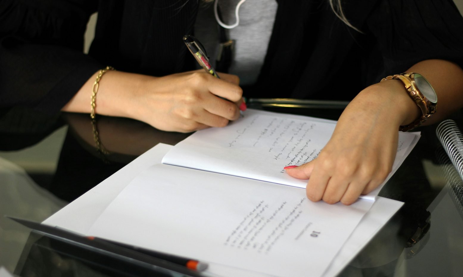 Close-up of a person taking notes on paper documents at a desk, with a pen in hand and a watch visible, illustrating paperwork for Freehold Property in Dubai.