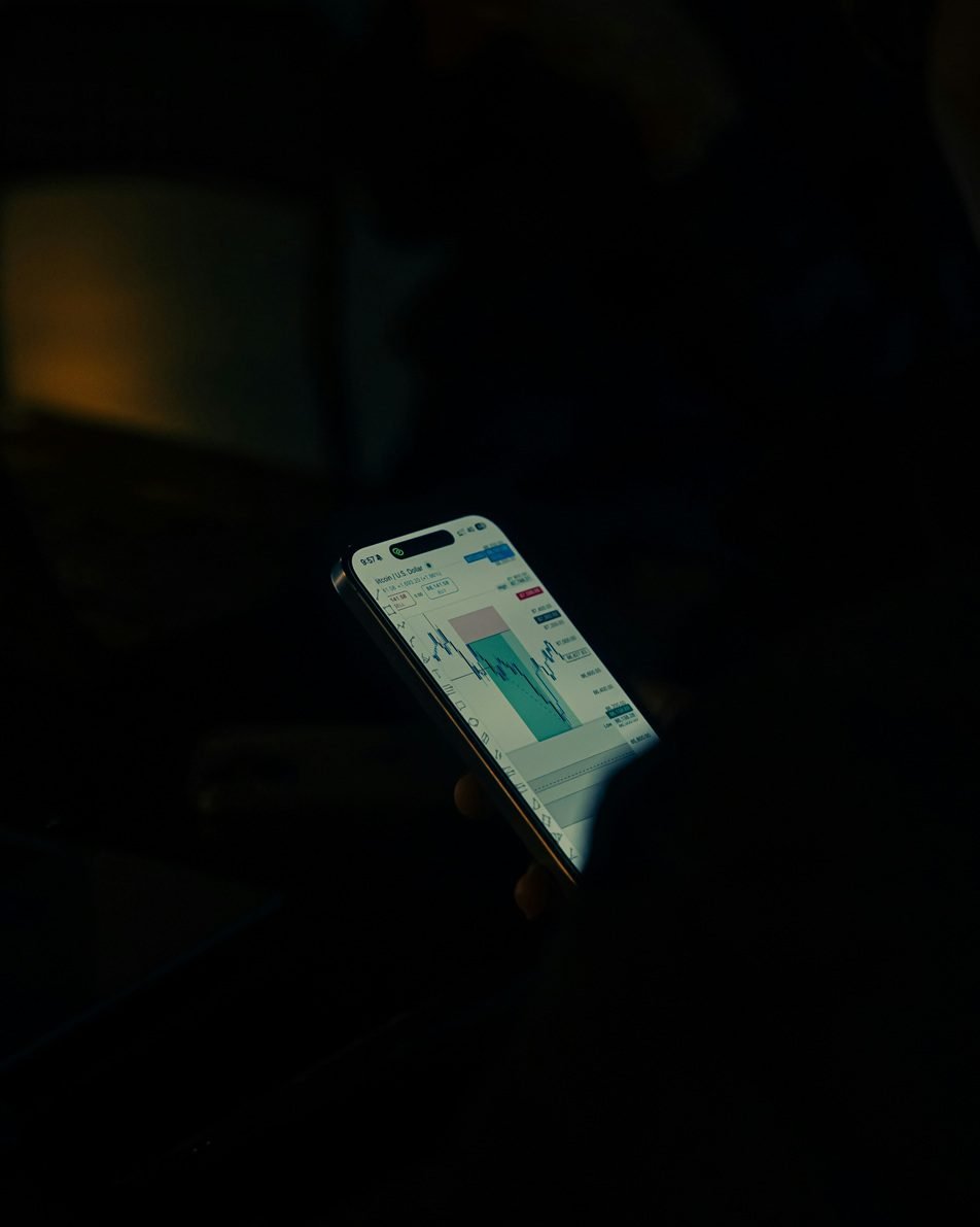 Person holding a smartphone displaying a financial trading chart, representing paper assets and market exposure as part of the best investments in Dubai.