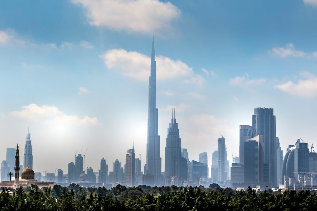 Dubai skyline with the Burj Khalifa rising above surrounding high-rise towers under a clear daytime sky, attached for Dubai golden visa article.