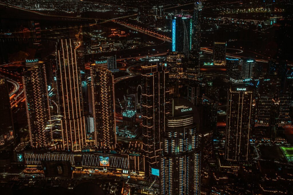 Dubai skyline at night showing high-density residential and commercial towers, illuminated roads, and active urban districts