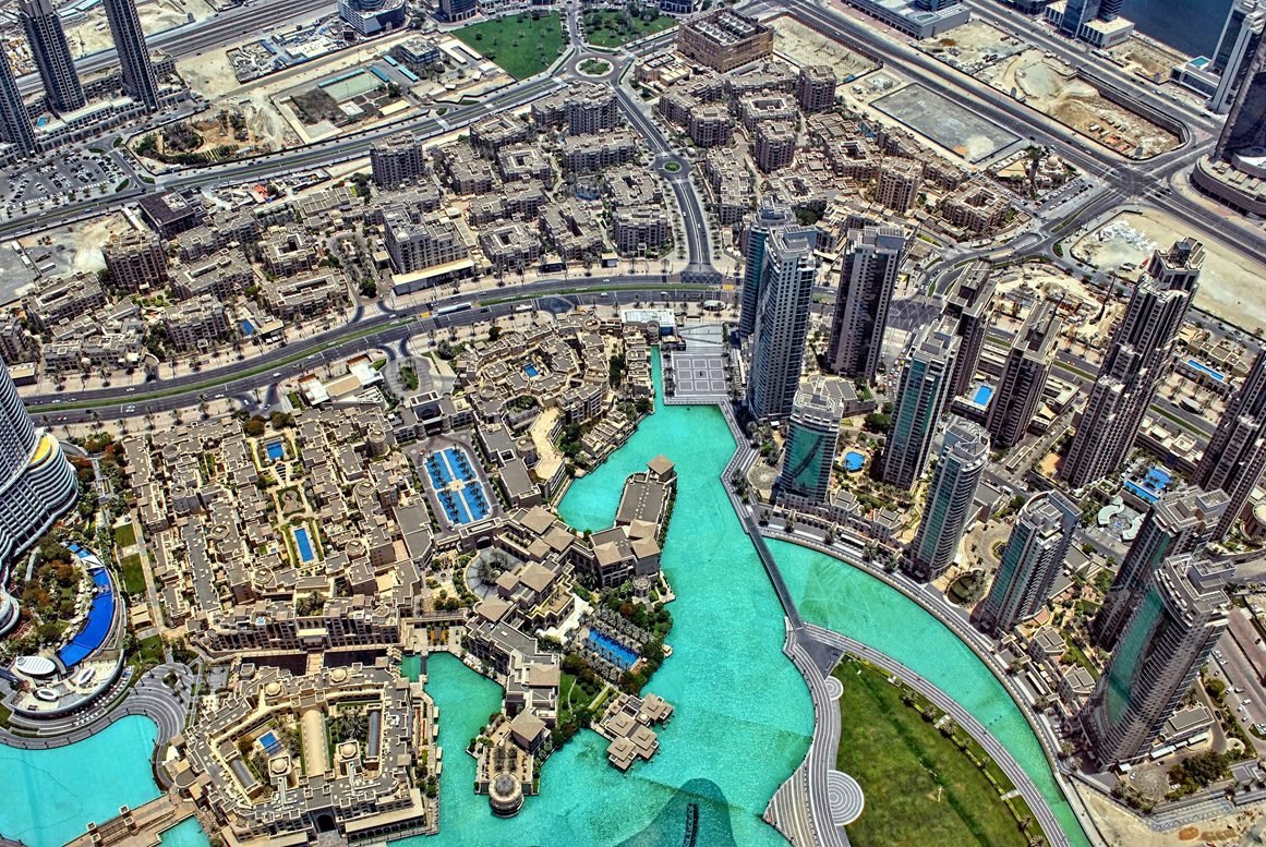 Aerial view of Downtown Dubai showing mixed-use residential towers, low-rise communities, roads, and turquoise waterways - Freehold vs Leasehold Property in Dubai