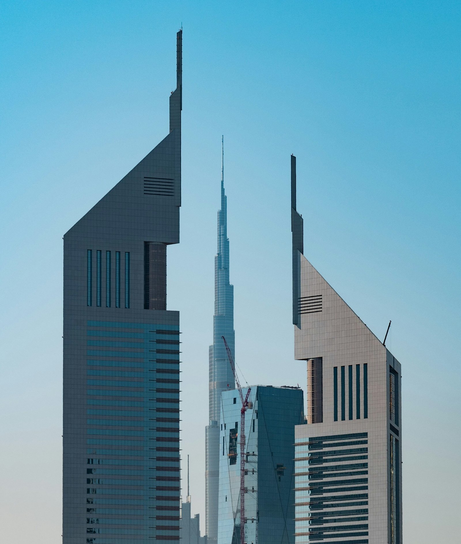Emirates Towers in Dubai’s DIFC area framing the Burj Khalifa in the distance under a clear blue sky.